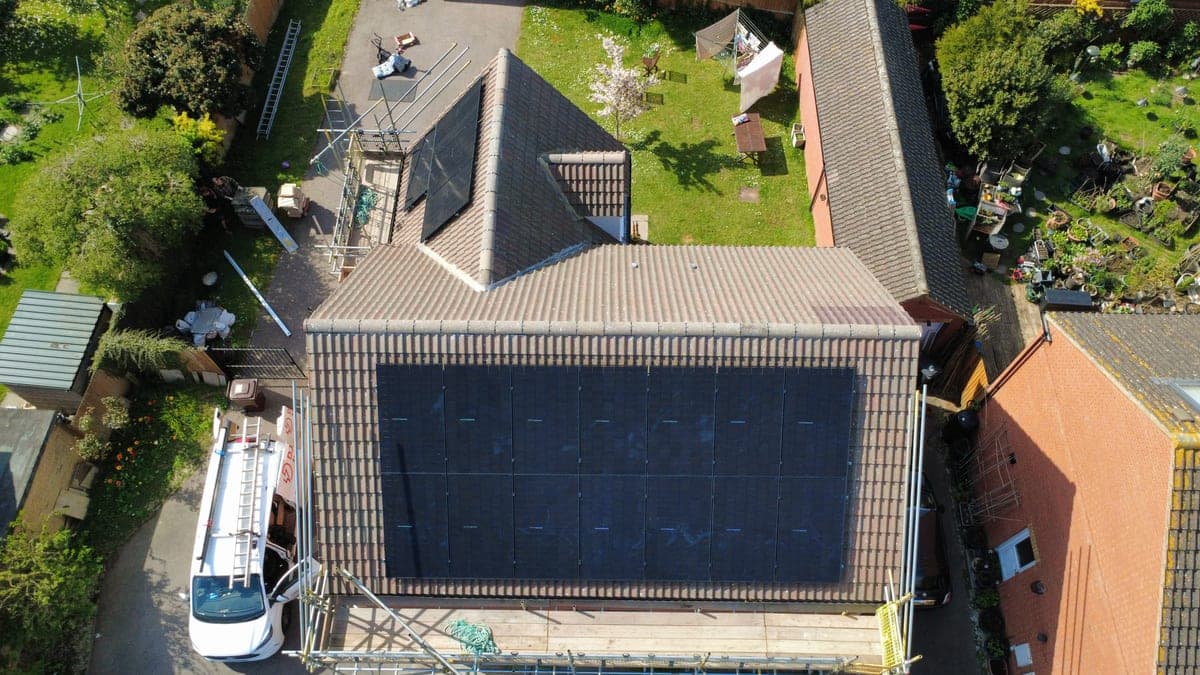 Drone aerial of a Djuka rooftop solar install with the branded van and scaffolding visible