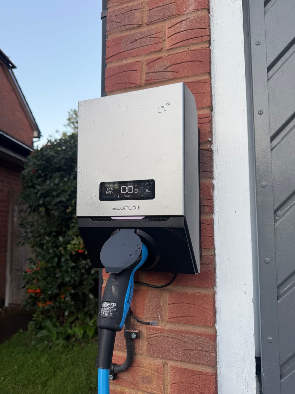 Home EV charger installed on a brick wall by Djuka, plugged in and charging
