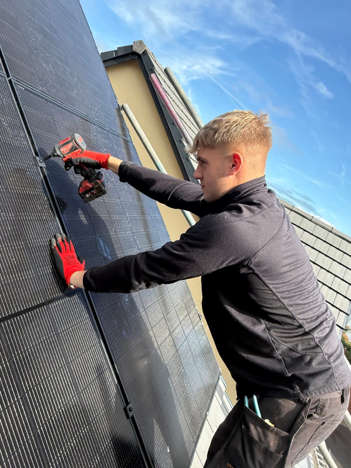 Djuka engineer drilling solar panel mounts on a Midlands rooftop