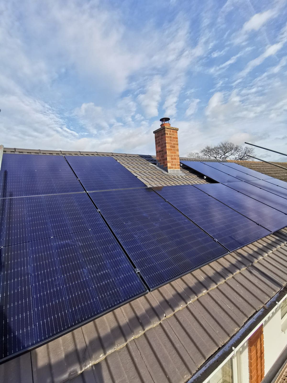 All-black solar panels installed around a brick chimney